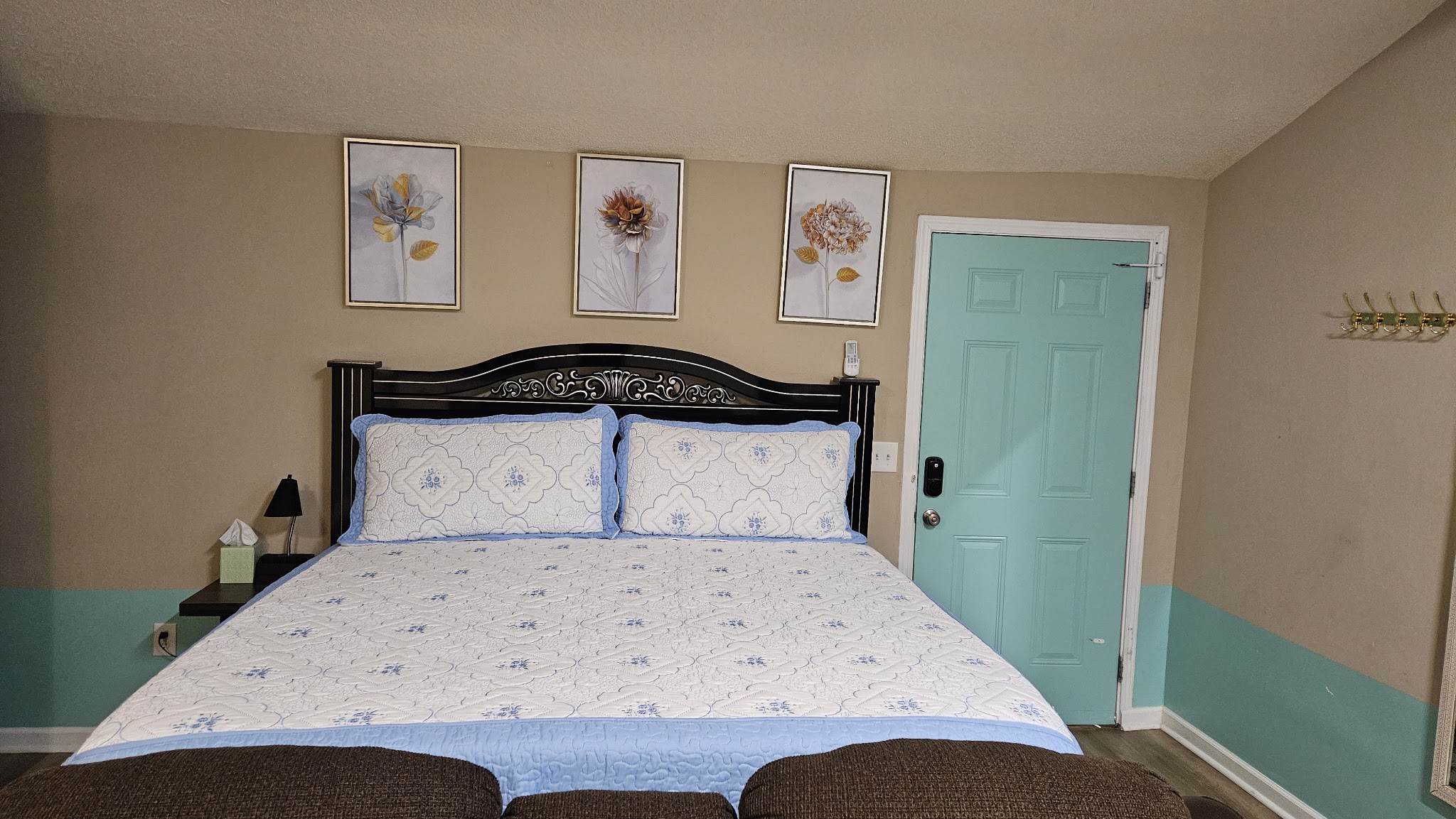 Bedroom after cleaning with a made king bed and teal door